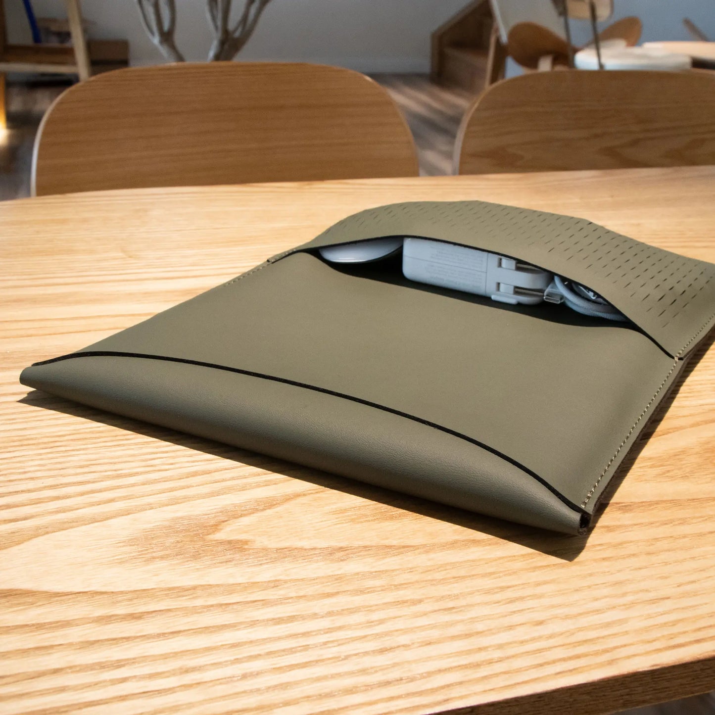 Closeup lifestyle shot of antibacterial 3-in-1 olive green MacBook leather sleeve.