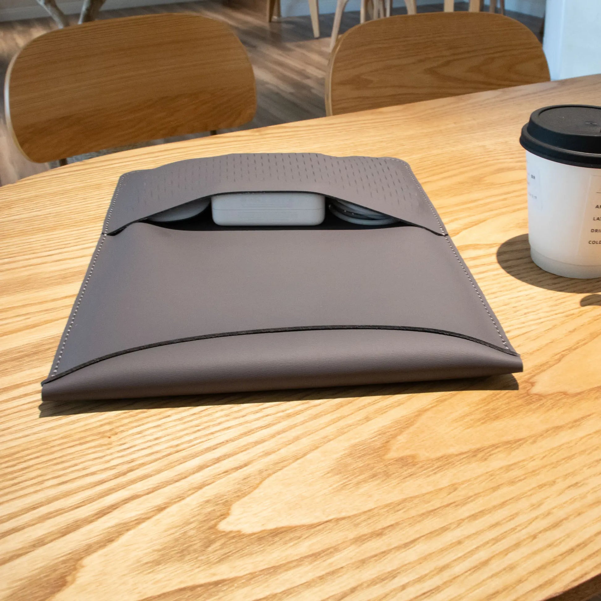 Lifestyle shot of antibacterial 3-in-1 MacBook leather sleeve in vintage gray.